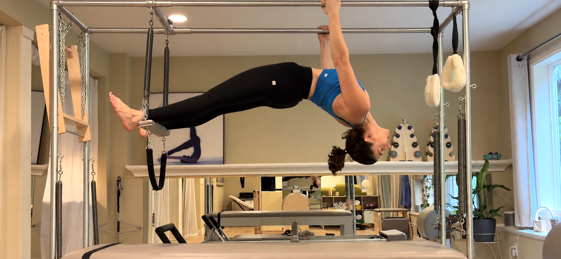 Tal demonstrating Pilates in a blue top on the Cadillac