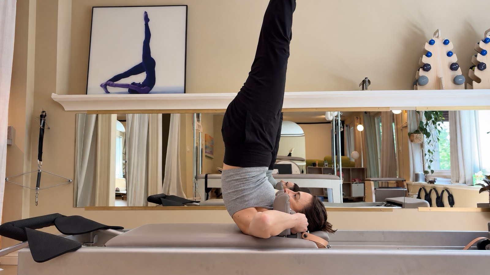 Tal on the reformer in an inverted Pilates position